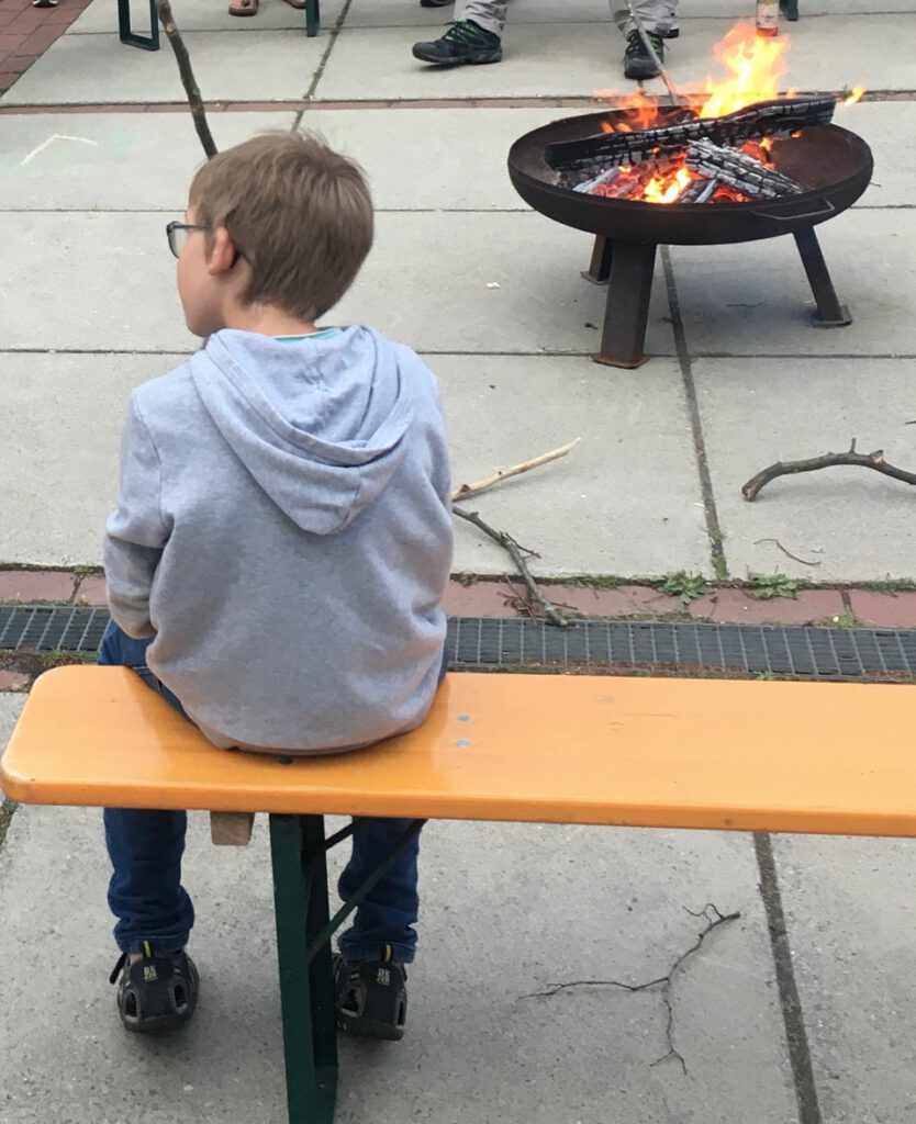 Kind auf Bank vor einer Feuerschale